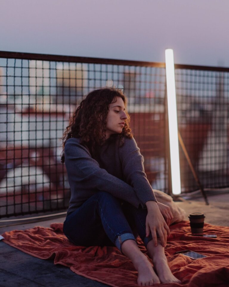 Unhappy young woman resting and sitting on the roof with city view. An unhappy young woman resting and sitting on the roof with city view. | © Foto: IMAGO | HalfPoint Images